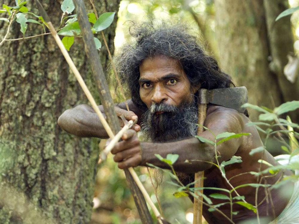 A Vedda elder draws a traditional bow in the forest near Dambana, Sri Lanka