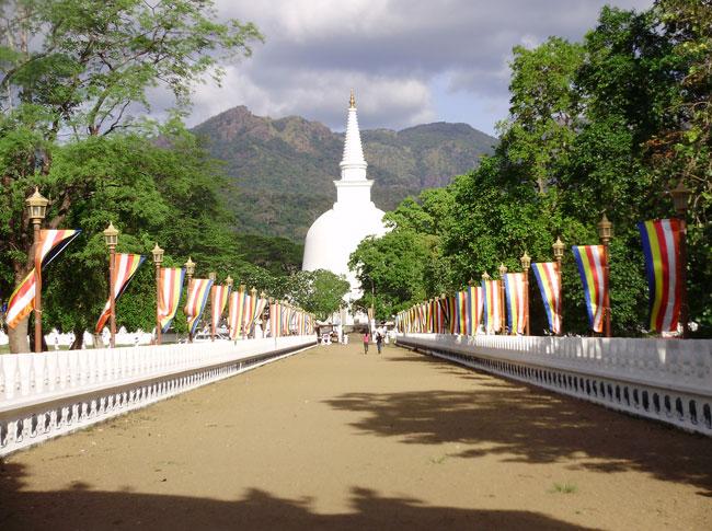 The white stupa of Mahiyangana Raja Maha Vihara framed by mountains, Sri Lanka
