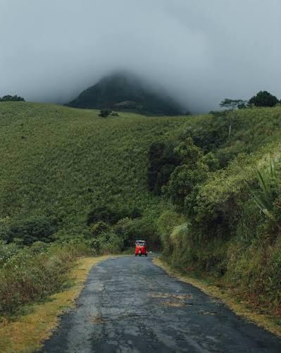 A red tuk-tuk on a misty mountain road on the way to Riverston, Sri Lanka
