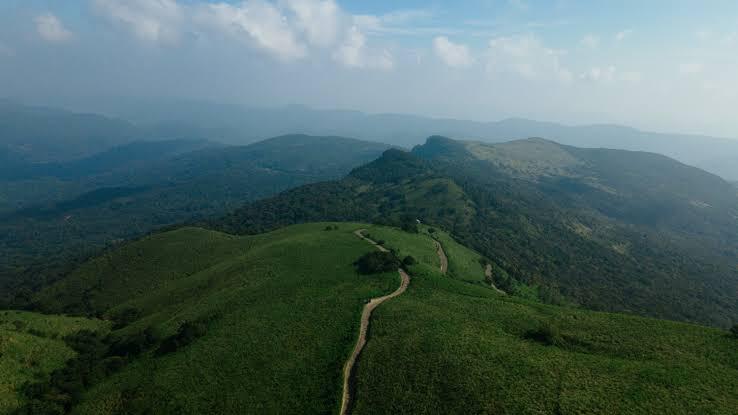 An aerial view of a dirt trail crossing the misty green grassland plateau at Riverston, Sri Lanka